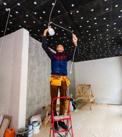 Electrician installer with a tool in his hands, working with cable on the construction site. Repair and handyman concept. House and house reconstruction